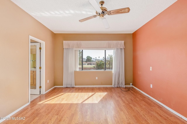 spare room with ceiling fan, baseboards, a textured ceiling, and wood finished floors