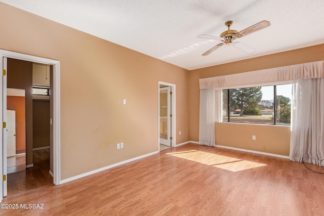 spare room with a textured ceiling, baseboards, light wood finished floors, and ceiling fan