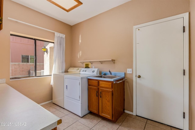 laundry room featuring light tile patterned floors, baseboards, separate washer and dryer, and a sink