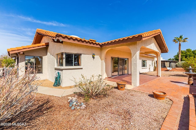 back of house with stucco siding and a patio