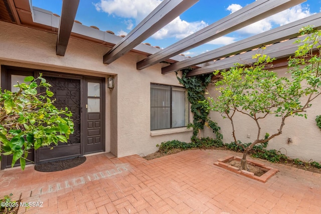 property entrance with stucco siding and a patio area