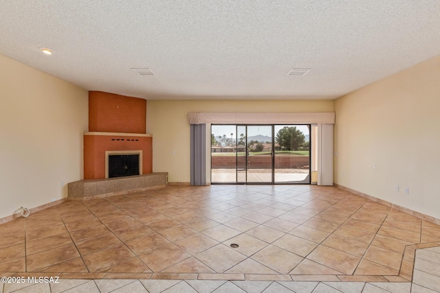 unfurnished living room featuring light tile patterned floors, a fireplace with raised hearth, baseboards, and a textured ceiling