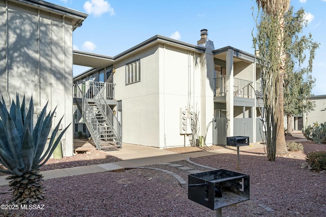 rear view of house featuring a patio, stairway, and a chimney