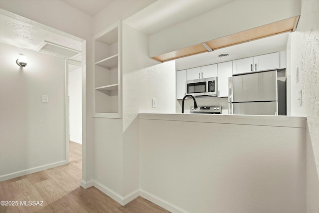 kitchen featuring appliances with stainless steel finishes, light wood-style flooring, and baseboards