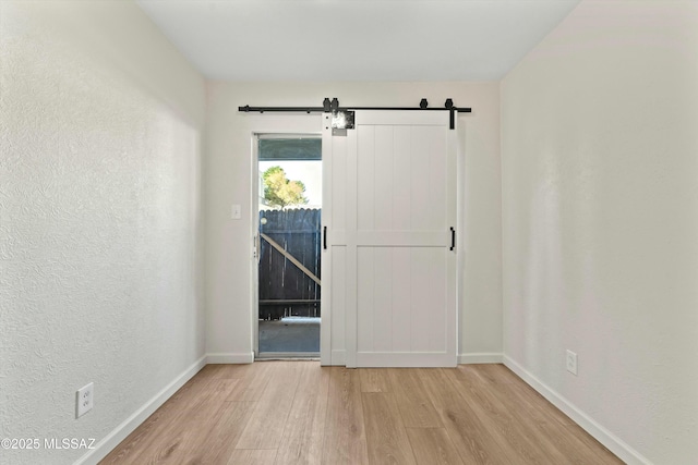 entryway featuring a barn door, baseboards, and wood finished floors