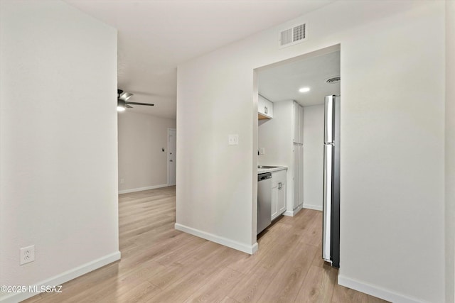 corridor featuring light wood-type flooring, baseboards, and visible vents