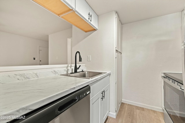 kitchen with baseboards, white cabinets, light wood-style flooring, light countertops, and a sink