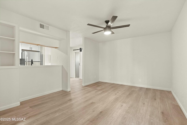 unfurnished room featuring baseboards, ceiling fan, light wood finished floors, and a barn door