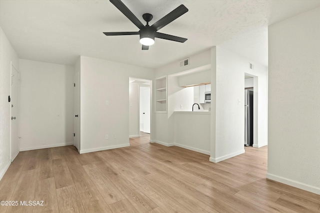 unfurnished living room with light wood finished floors, baseboards, visible vents, and ceiling fan