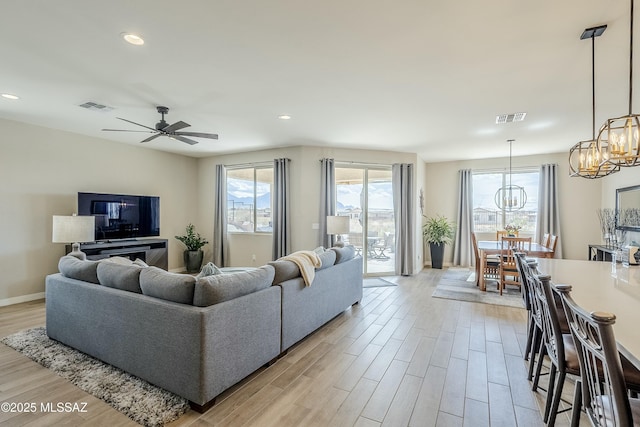 living area featuring recessed lighting, visible vents, ceiling fan with notable chandelier, and light wood-type flooring