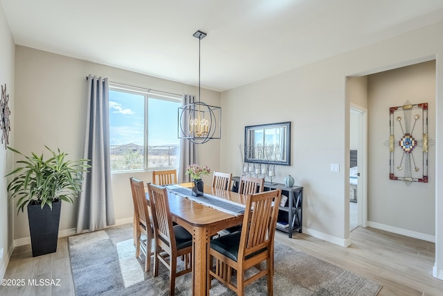 dining space with a notable chandelier, light wood-type flooring, and baseboards