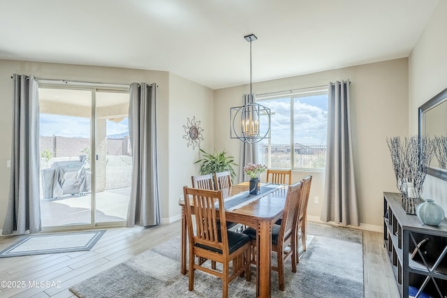 dining space featuring baseboards, a notable chandelier, and light wood-style flooring