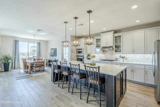 kitchen featuring gas cooktop, a notable chandelier, visible vents, and under cabinet range hood