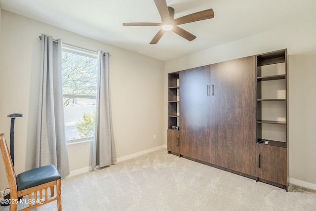 interior space featuring ceiling fan, baseboards, and light carpet