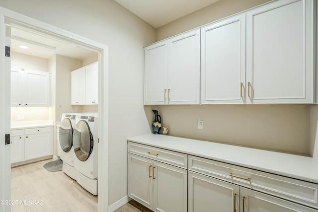 laundry area featuring washer and dryer, cabinet space, and light wood-style floors