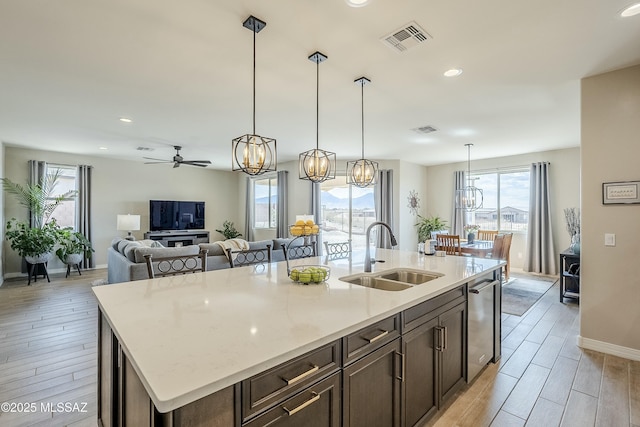 kitchen featuring visible vents, a sink, light wood-type flooring, ceiling fan with notable chandelier, and stainless steel dishwasher