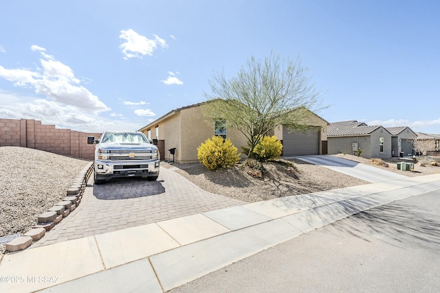 view of front of house with fence, a tiled roof, stucco siding, a garage, and driveway