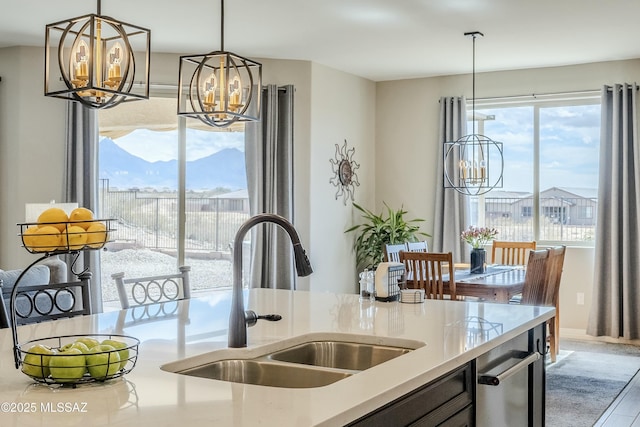 kitchen with a sink, decorative light fixtures, light stone counters, and a chandelier