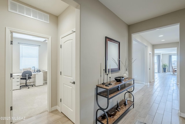 hall featuring baseboards, visible vents, a wealth of natural light, and wood tiled floor