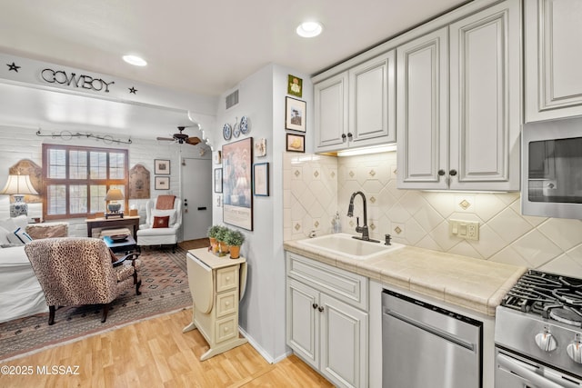 kitchen with visible vents, open floor plan, stainless steel appliances, light wood-type flooring, and a sink