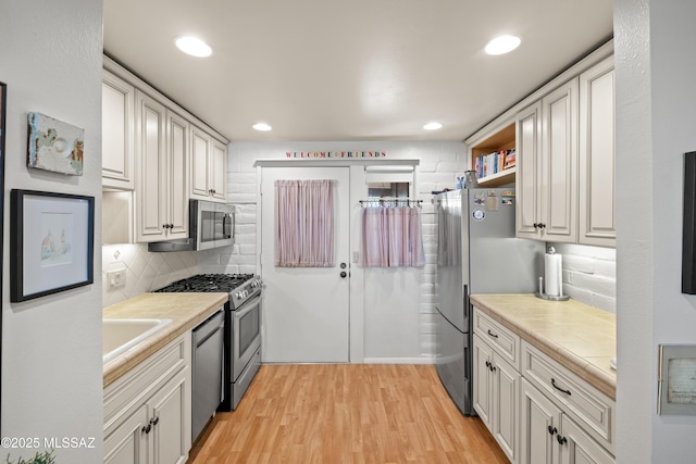 kitchen with stainless steel appliances, recessed lighting, decorative backsplash, and light wood-style floors