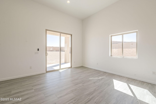 empty room featuring light wood-style floors, baseboards, and a wealth of natural light