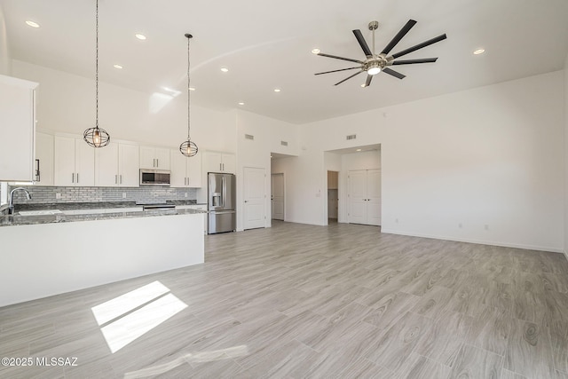 kitchen with open floor plan, stainless steel appliances, backsplash, and a sink