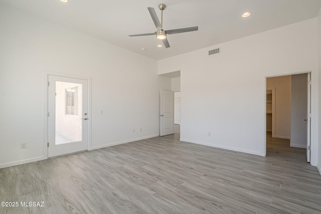 unfurnished bedroom with recessed lighting, visible vents, light wood-style flooring, a high ceiling, and baseboards