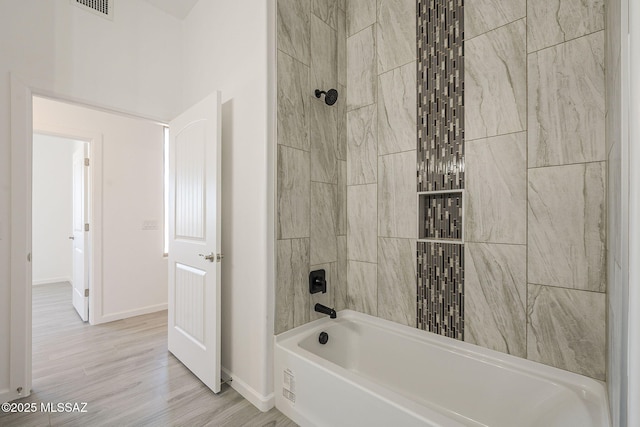 full bath featuring shower / bath combination, visible vents, baseboards, and wood finished floors