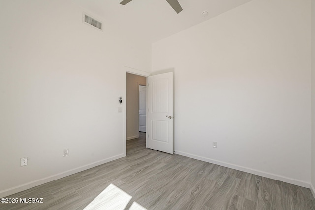 spare room with light wood finished floors, a ceiling fan, visible vents, and baseboards