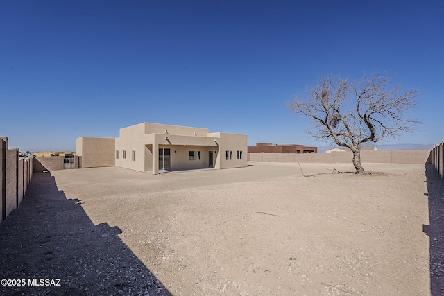 back of house with a fenced backyard and stucco siding