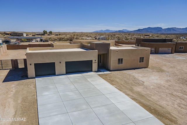 pueblo revival-style home featuring a garage, concrete driveway, a mountain view, and stucco siding