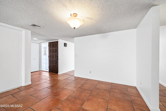 empty room with visible vents, a textured ceiling, and tile patterned floors