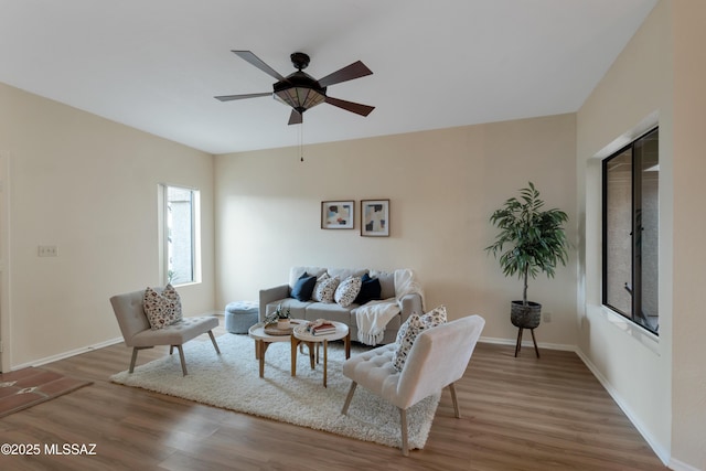 living room with a ceiling fan, baseboards, and wood finished floors