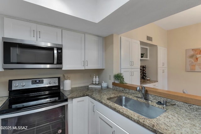 kitchen with light stone counters, visible vents, appliances with stainless steel finishes, white cabinetry, and a sink