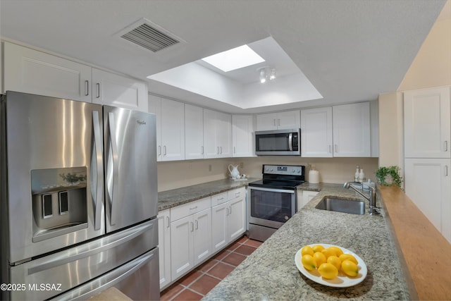 kitchen with visible vents, a raised ceiling, stainless steel appliances, white cabinetry, and a sink