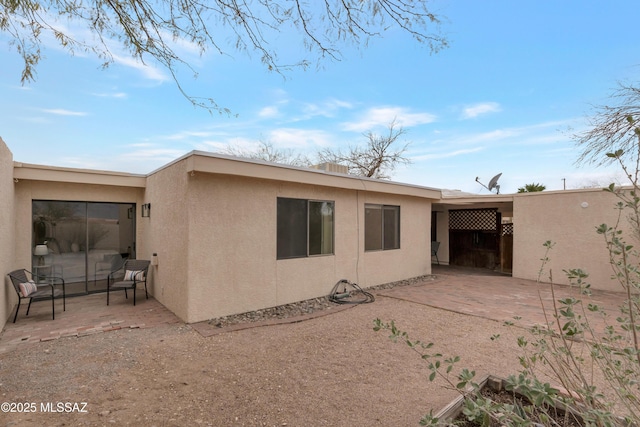 rear view of house with a patio and stucco siding