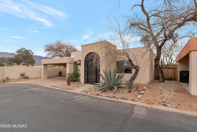 view of front facade featuring fence private yard, a gate, a mountain view, and stucco siding