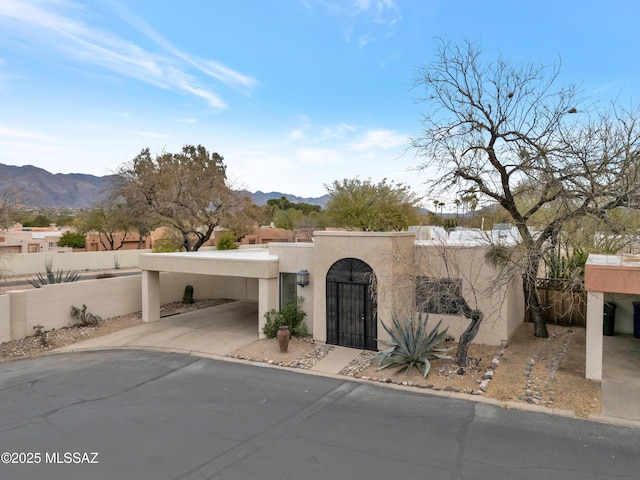 adobe home with a fenced front yard, a gate, a mountain view, and stucco siding