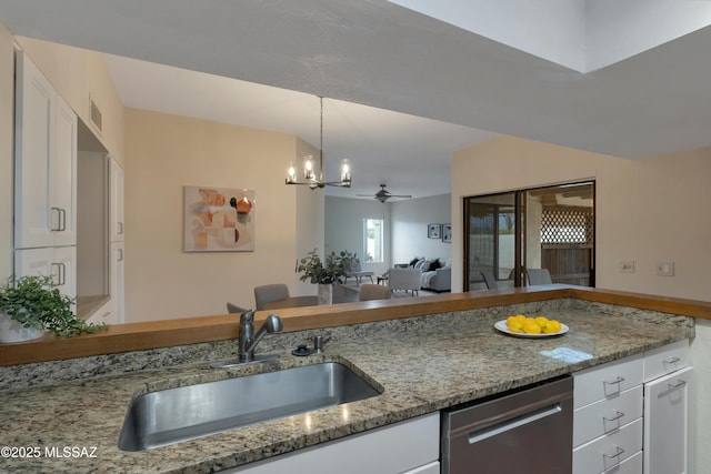 kitchen featuring stainless steel dishwasher, open floor plan, white cabinetry, a sink, and light stone countertops