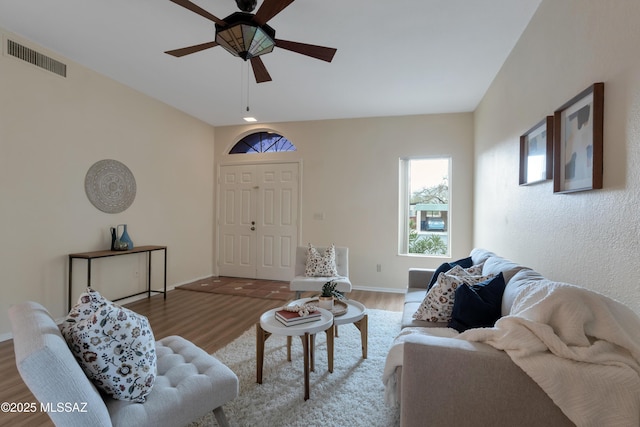 living area with a ceiling fan, visible vents, baseboards, and wood finished floors