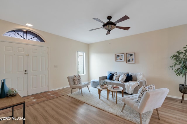 living area featuring ceiling fan, baseboards, and wood finished floors