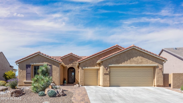 view of front of home with a garage, a tile roof, driveway, and stucco siding