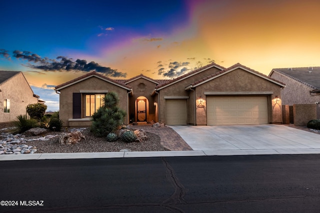 ranch-style home featuring concrete driveway, an attached garage, a tile roof, and stucco siding