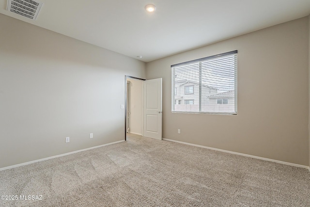 empty room featuring carpet floors, baseboards, and visible vents