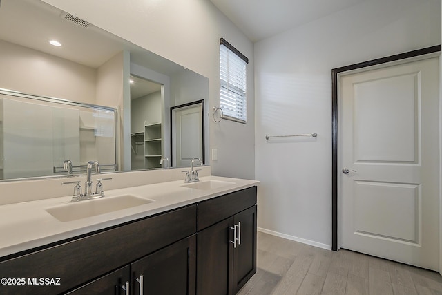 bathroom featuring wood finished floors, a sink, visible vents, and baseboards