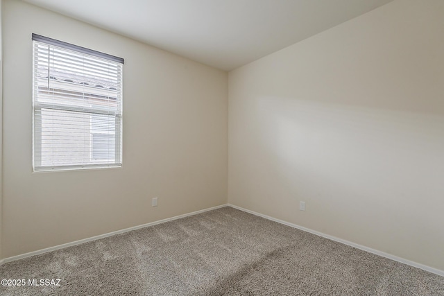 carpeted spare room featuring baseboards