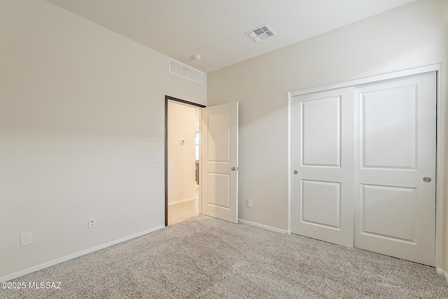 unfurnished bedroom with a closet, visible vents, light carpet, and baseboards