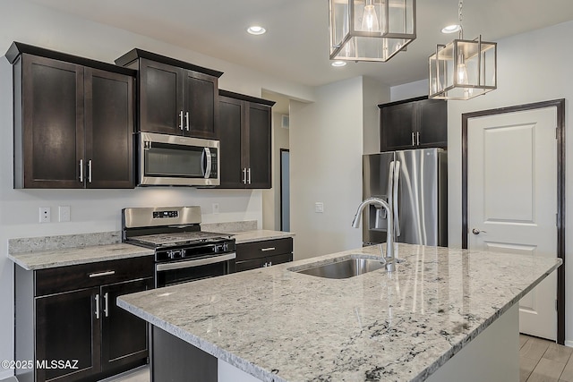 kitchen with light stone countertops, stainless steel appliances, a sink, and recessed lighting