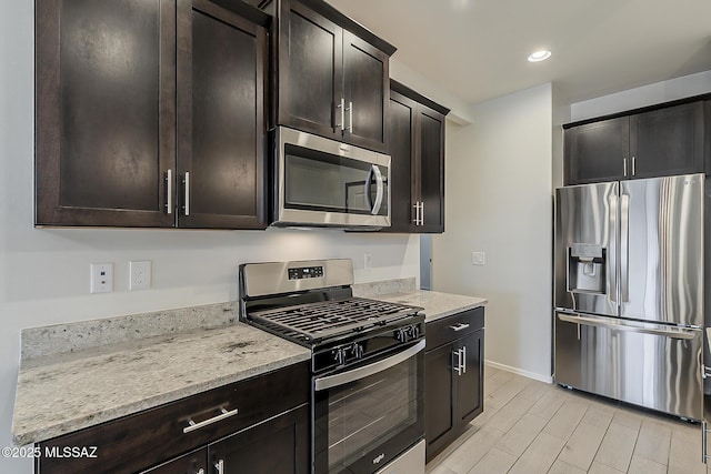 kitchen with dark brown cabinetry, baseboards, appliances with stainless steel finishes, light stone counters, and recessed lighting